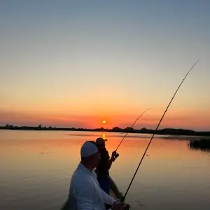Pescari in barca la apus pe canalele Deltei